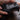 Thumbnail for Person holding a black gaming controller on a wooden surface