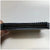 A close-up of a black multi-pin electronic connector plug held by a hand against a plain light background.