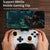 Gaming controller with smartphone displaying a game, held by hands on a wooden surface.
