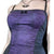 A close-up of a person wearing a purple and black lace corset-style camisole top with thin black straps and a small black bow at the neckline, against a plain white background.